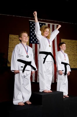 Children stand on a podium following a martial arts competition.