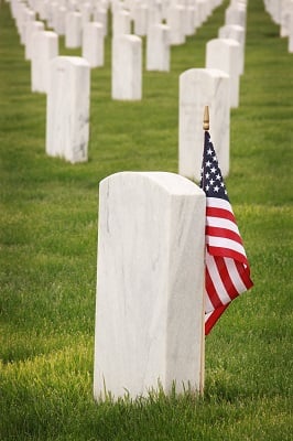 An American flag over an unmarked tombstone.