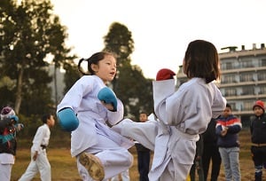 Photo by Jyotirmoy Gupta on Unsplash. Two girls train karate wearing gi uniforms and sparring gloves.