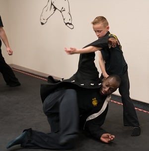 A child practices kung fu with help from an adult training partner. 