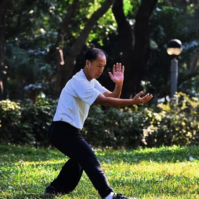 Photo by Mark Hang Fung So on Unsplash. Man practices tai chi in a park.