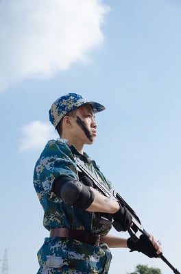A soldier in camo uniform stands at attention. martial arts in the military