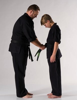 Instructor tying belt on child