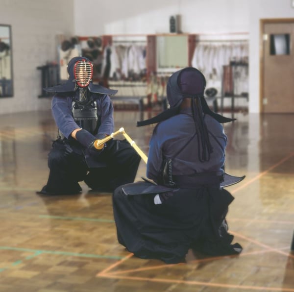 Kendo students wearing armor and holding shinai training swords prepare to spar.