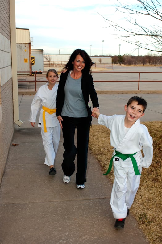 A mother walks her two children to martial arts. 