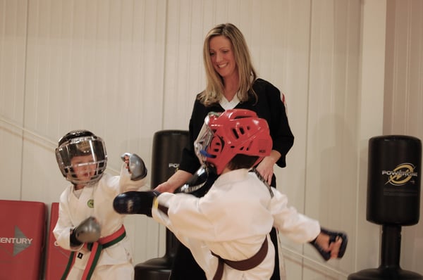 A martial arts instructor watches two young students spar.